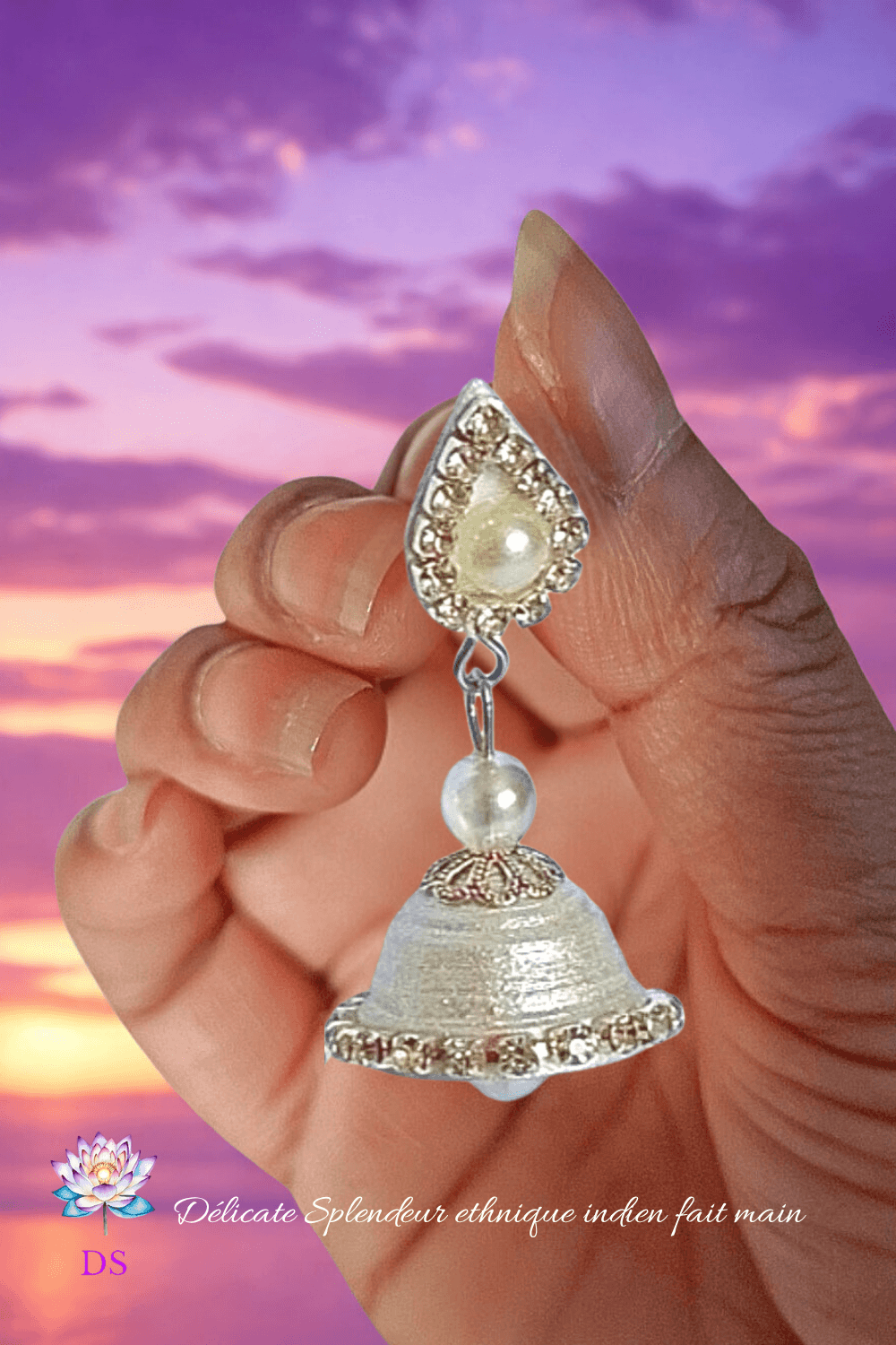 Légèreté d'un Jumka argenté entre les doigts, sous un ciel violet et rosé.